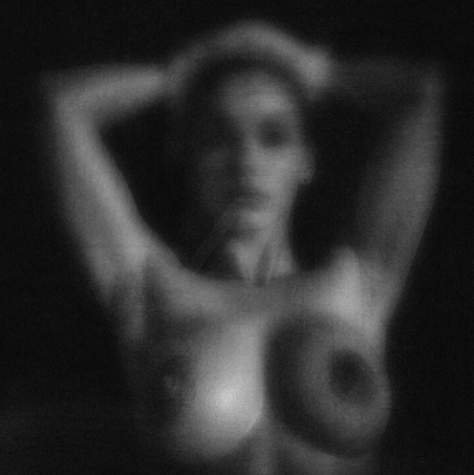 Black and white artistic nude photography with soft focus, showing abstract human form in shadow and light.